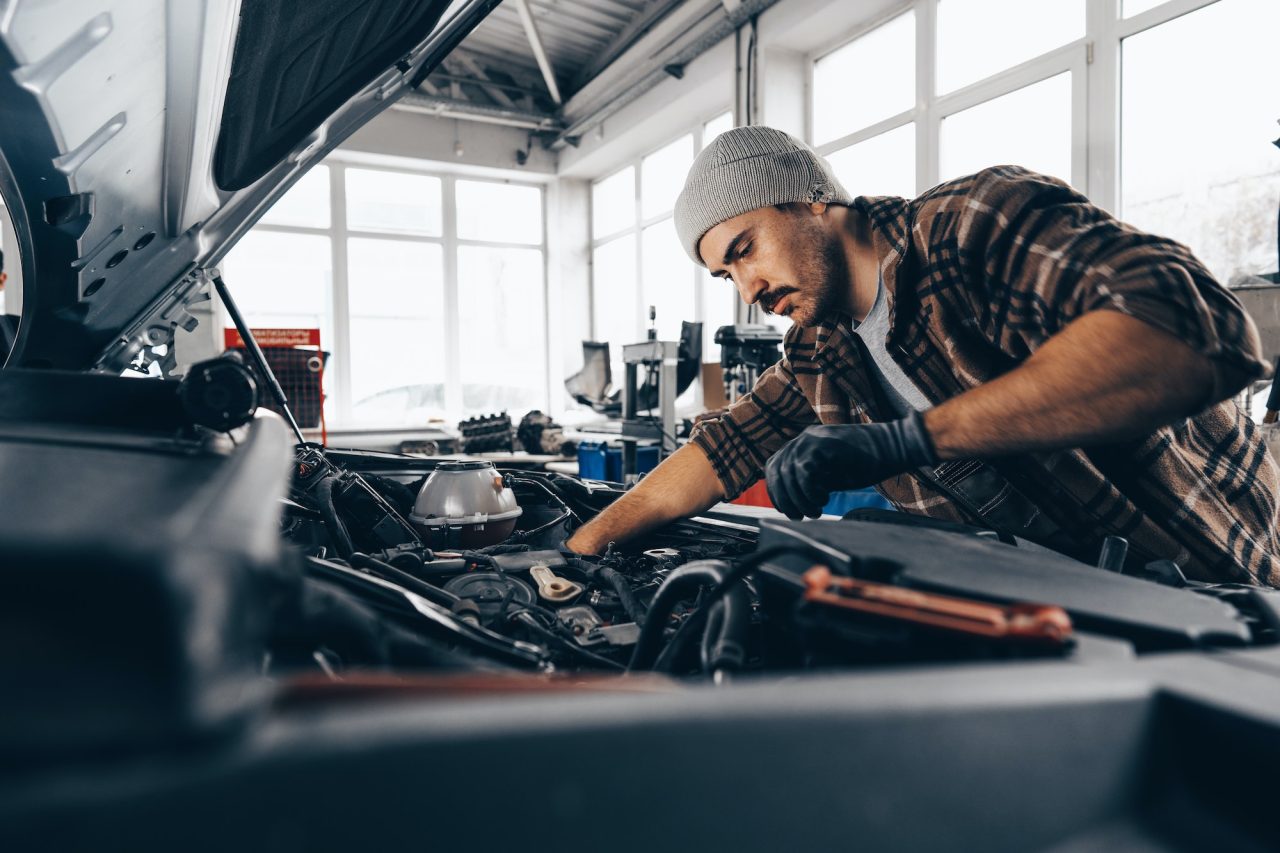 auto mechanic inspecting under a car hood
