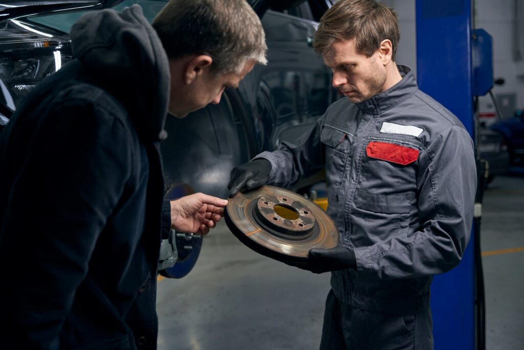 Man holding brake disc, talking with client