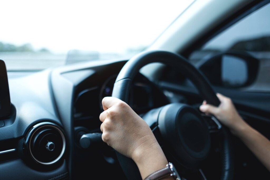 Person holding a steering wheel while driving.