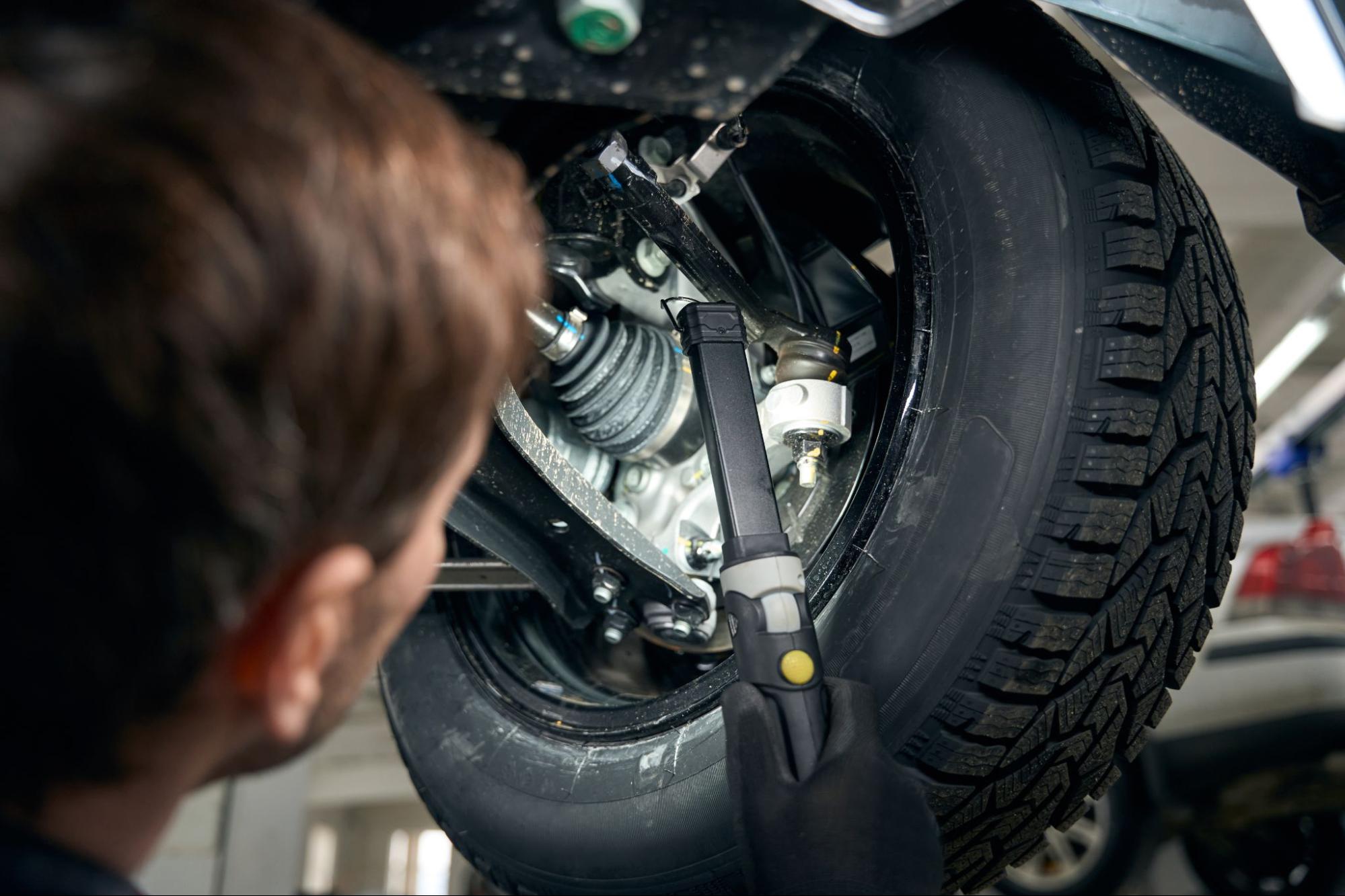 A mechanic inspects the suspension strut boot collars in an auto workshop.