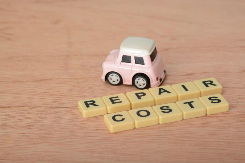A toy car beside the letter blocks spelled “Repair Costs”