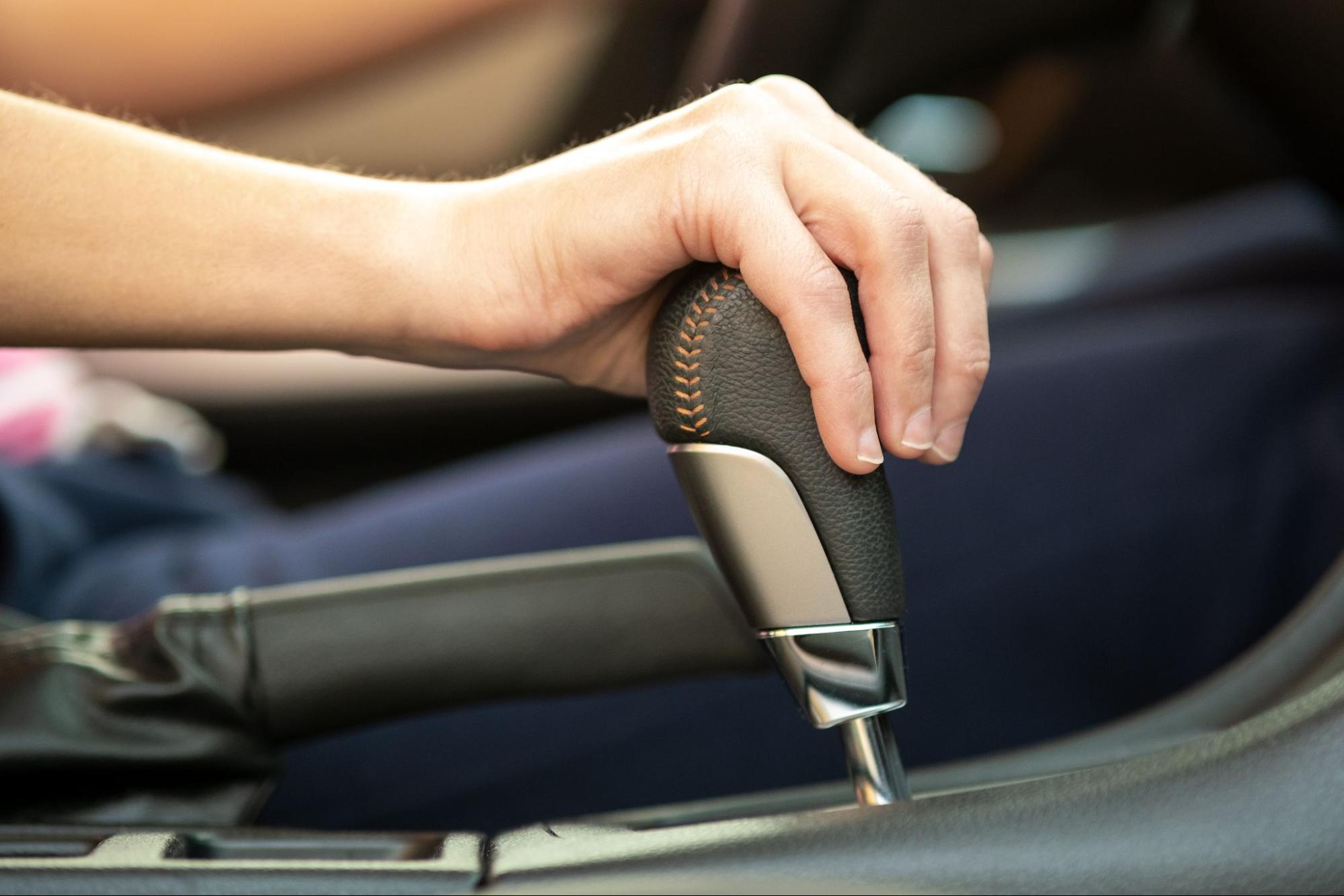 Woman with her hand on a gear shift.