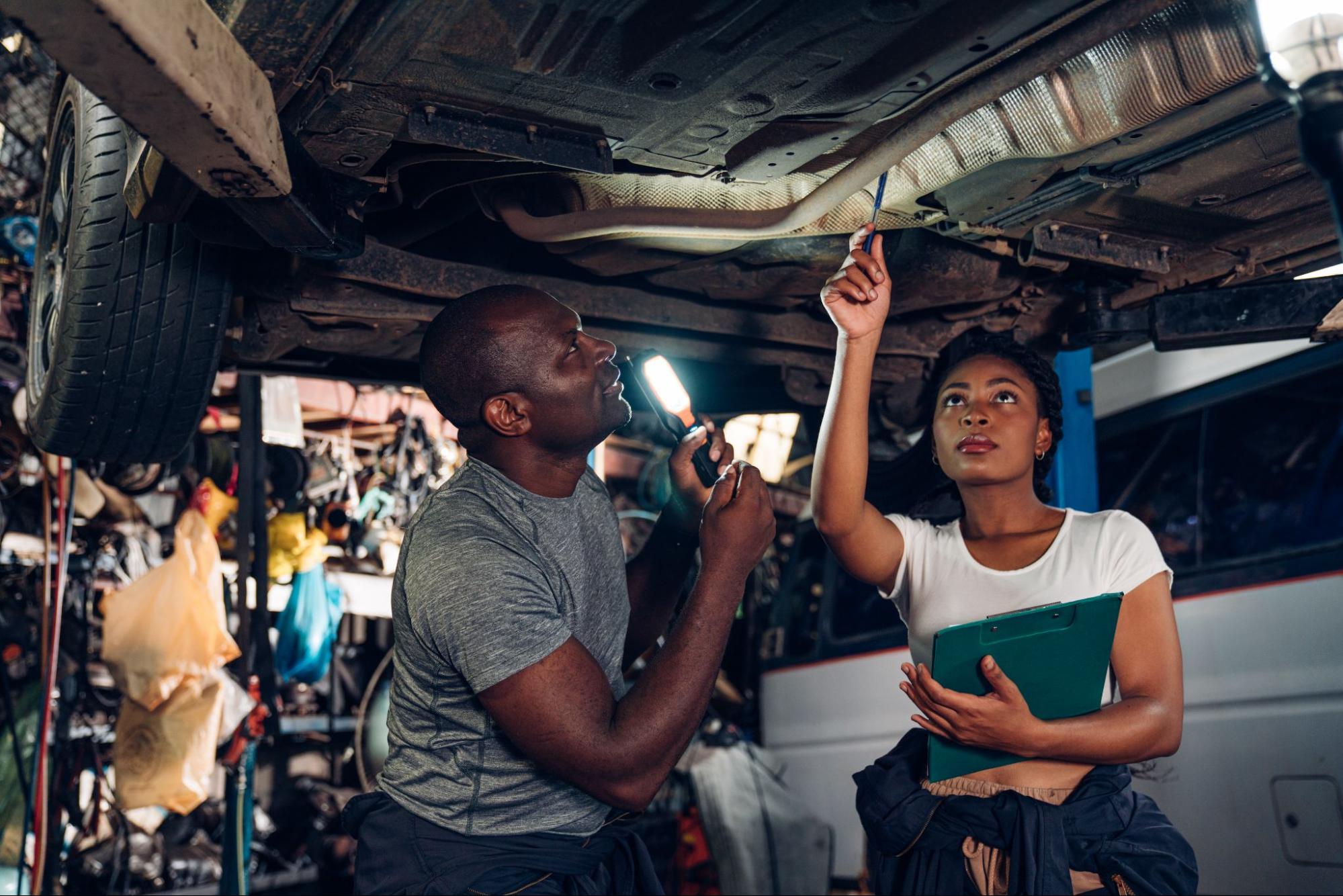 Mechanics diagnose engine issues at a car repair shop to determine a repair cost estimate.