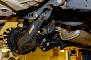 A close-up of a car brake assembly and suspension components exposed with the wheel removed.