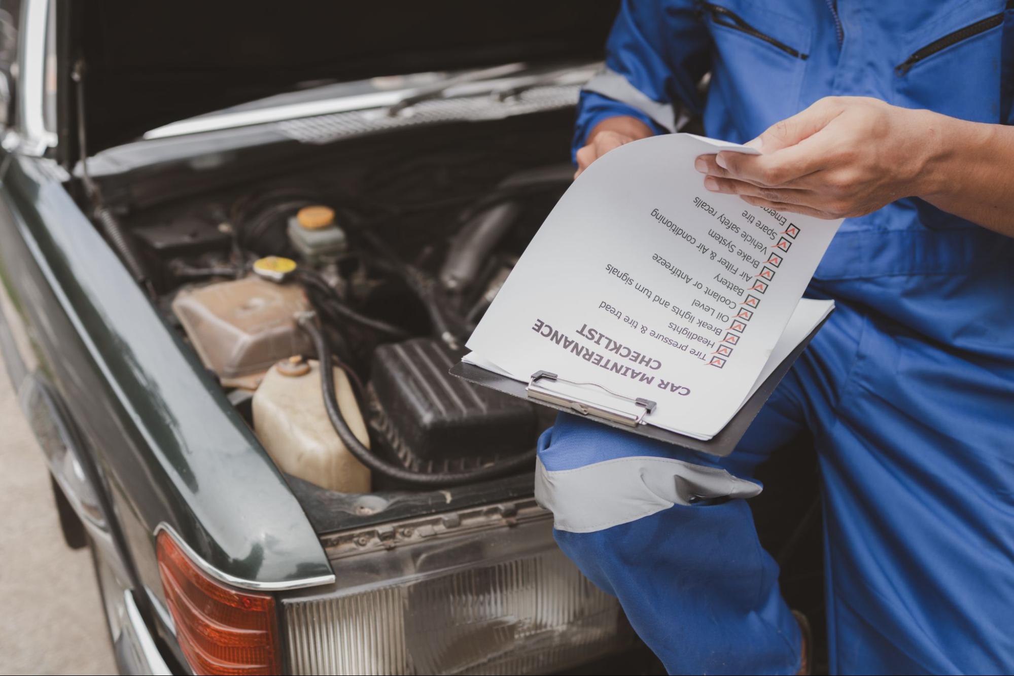 Car mechanic reviewing a checklist before inspecting a vehicle for a repair