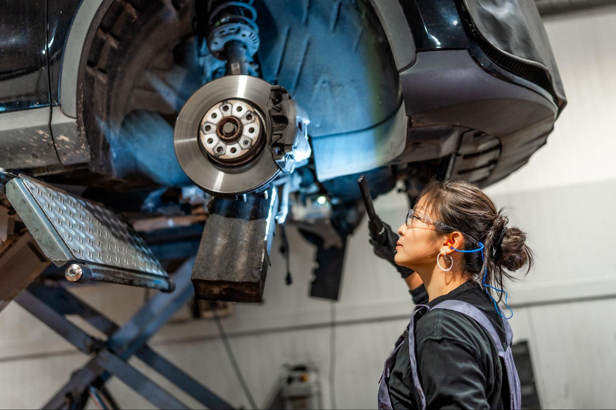 Female mechanic carefully inspecting a vehicle’s brake system